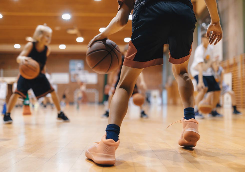 view of young basketball player mid-dribble with other players blurred in the background
