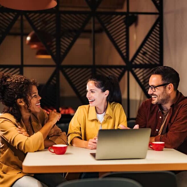 smiling colleges in front of laptop